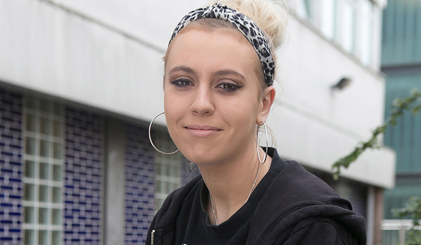 Close up photo of woman with blonde hair, smiling, wearing dark hoody.